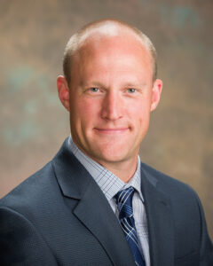 TJ, in a suit, smiles at the camera for the photo